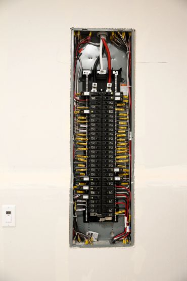 Open electrical panel with circuit breakers and wiring.