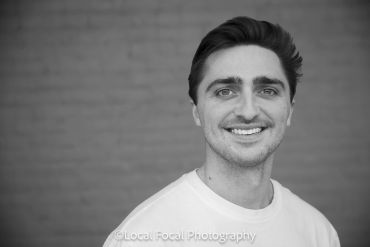 Young man smiling at the camera in black and white portrait.