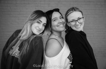 Three happy women smiling side by side in black and white.