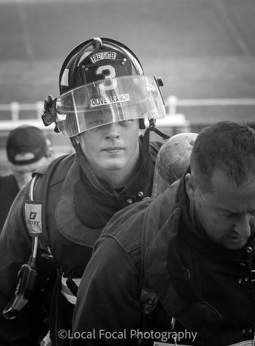 Firefighters in action, one with helmet labeled Olive Branch.