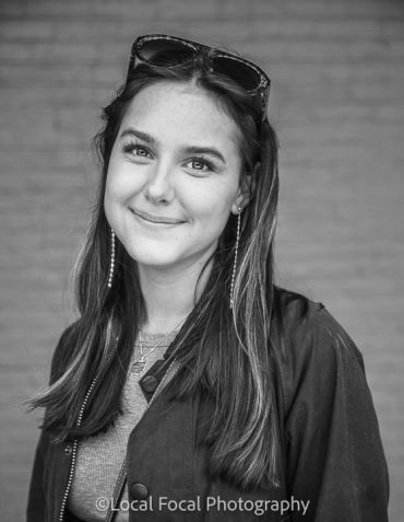 Portrait of a smiling young woman wearing sunglasses on her head.