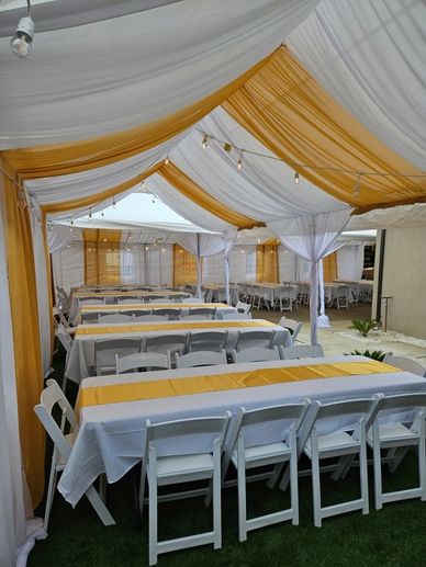 Elegant outdoor event setup with white and gold draped canopy and tables.