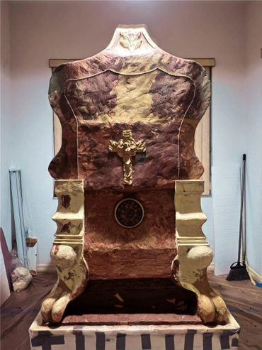 Ornate chair with a cross design in a rustic room.