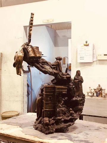 Intricate bronze sculpture depicting multiple human figures and a building.