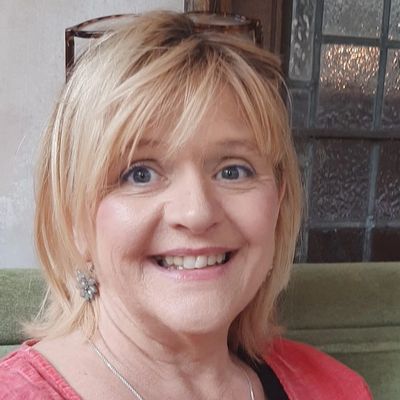 Smiling middle-aged woman with blonde hair indoors.