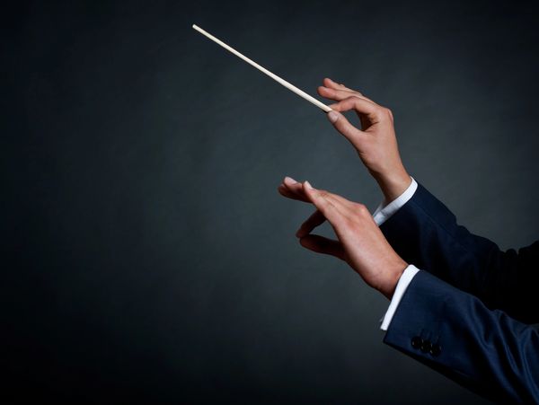 image of a male orchestra conductor directing with his baton in concert
