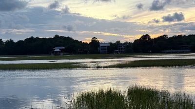 Calm lake with grassy patches at sunset.