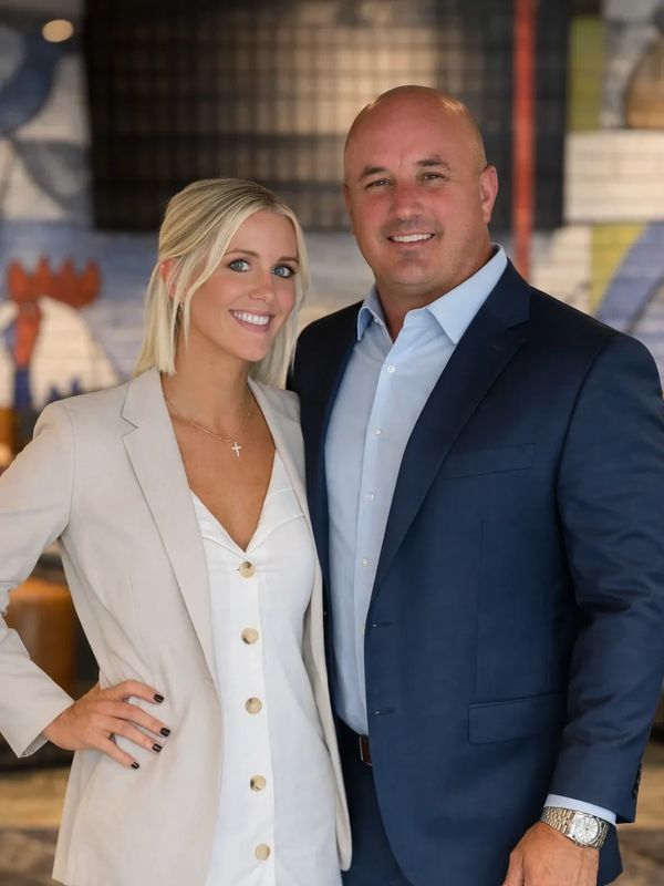 A smiling couple dressed in formal attire posing indoors.