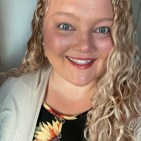 Smiling woman with curly blonde hair and bright eyes.