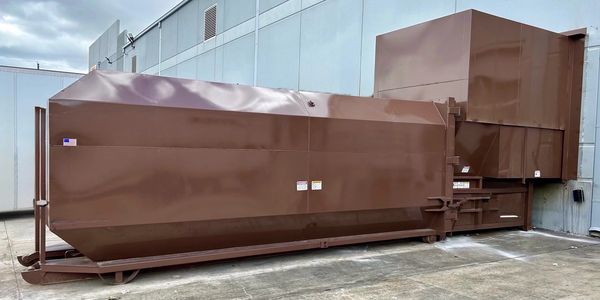 Large industrial stationary waste compactor with walk on deck and full enclosure, securing assets from outside intrusion.