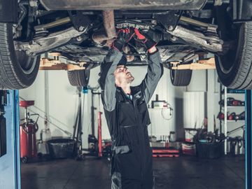 Saskatoon auto mechanic from Tech 7 Auto Repair under car to diagnose and repair drivetrain issues. 