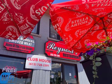 Exterior view of Reynold's Restaurant with red Stella Artois umbrellas.