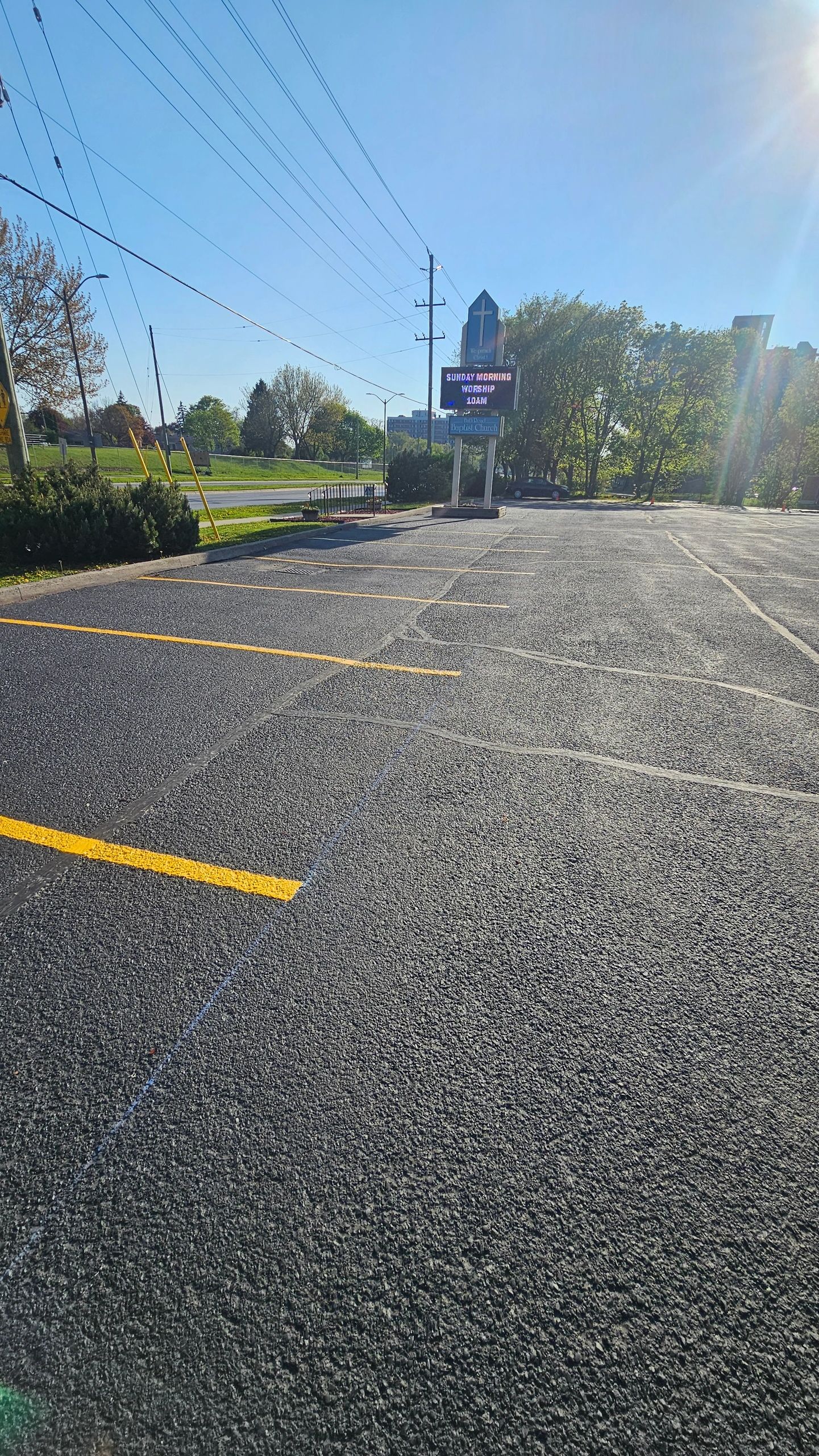 Empty church parking lot with a sign announcing Sunday worship at 10 AM.