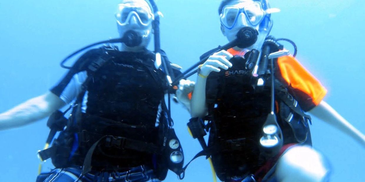 Two scuba divers underwater with full gear.