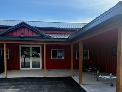 Red building with a metal roof and wooden porch posts.