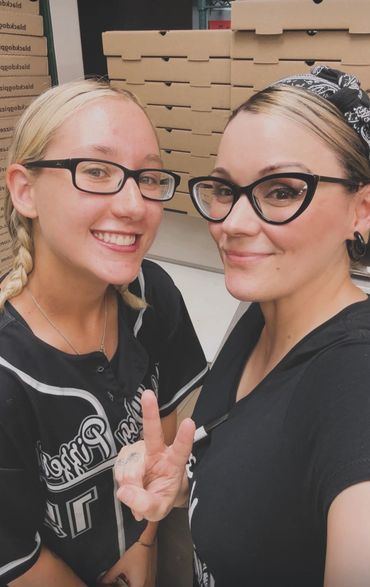 Two employees in a smiling selfie for the camera.  