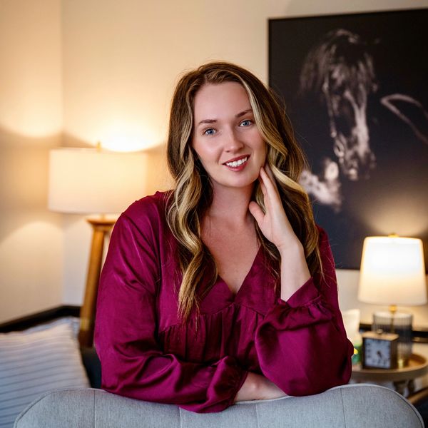 Smiling woman in a maroon blouse posing indoors.