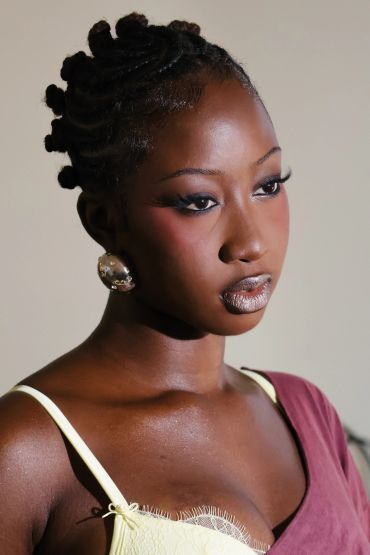 Portrait of a woman with braided hair and bold makeup.