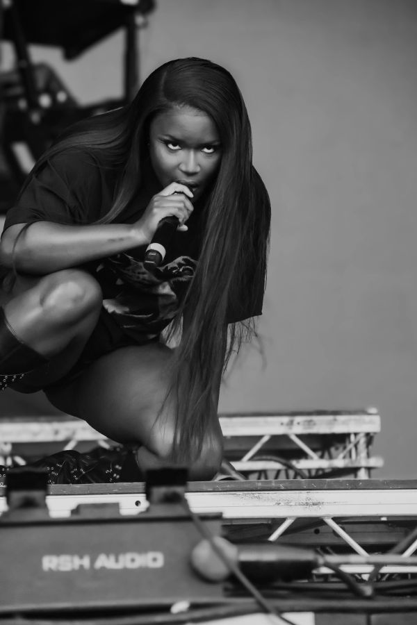 Female performer intensely singing on stage, crouched down with microphone.