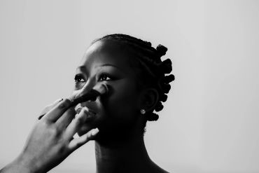 A woman getting makeup applied on her nose.