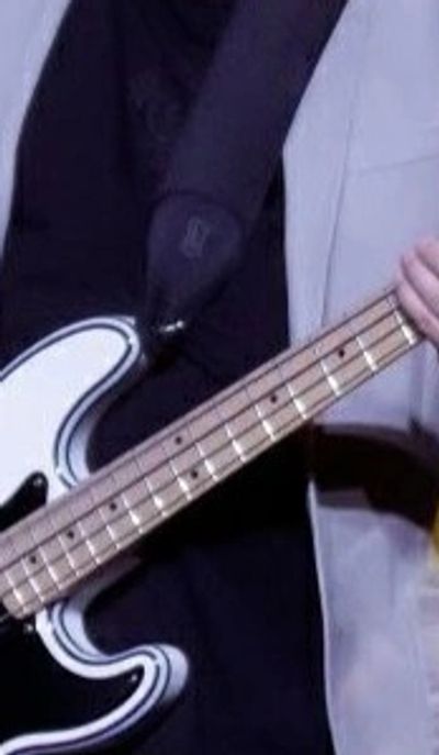 Close-up of a person playing an electric bass guitar.