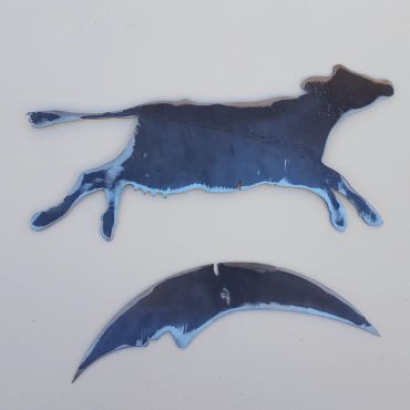 Two metal art pieces, a running cow and a crescent shape.