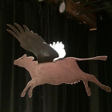 Metal sculpture of a pig with wings.