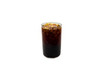 A tall glass filled with a dark iced beverage, topped with orange zest.