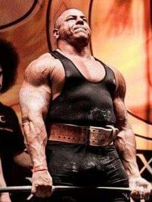 Muscular man lifting a heavy barbell during a strength competition.