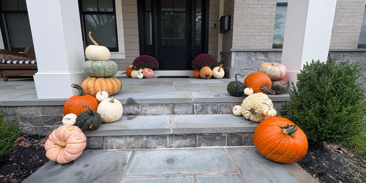 Autumn pumpkin and gourd display on stone porch steps.