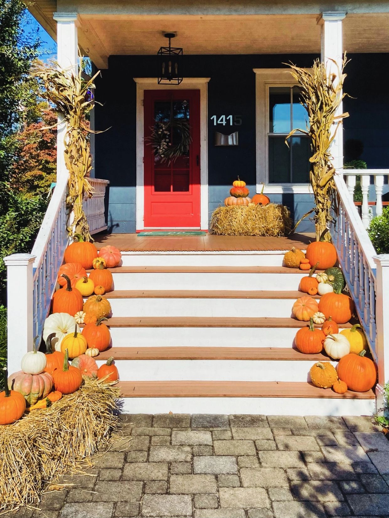 Fall-themed porch with pumpkins and cornstalks.