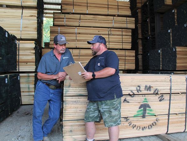 Two men inspecting lumber stacks.