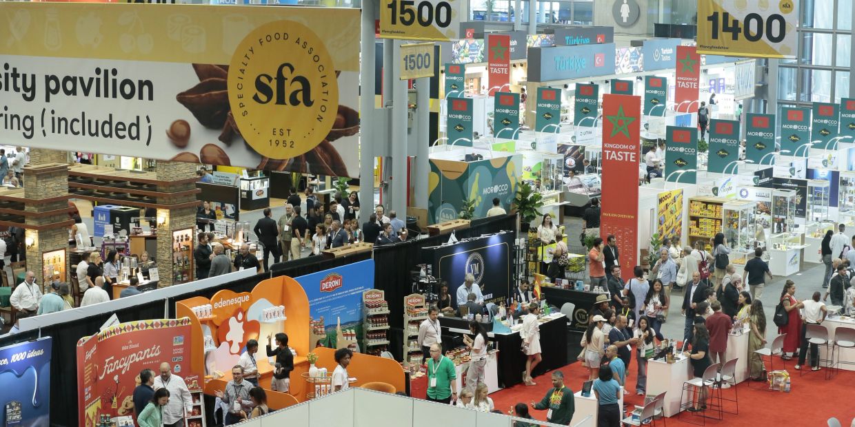 Busy specialty food association pavilion at a trade show.