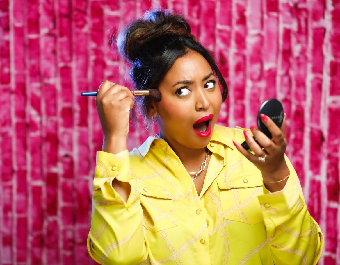 Woman applying makeup looking surprised.