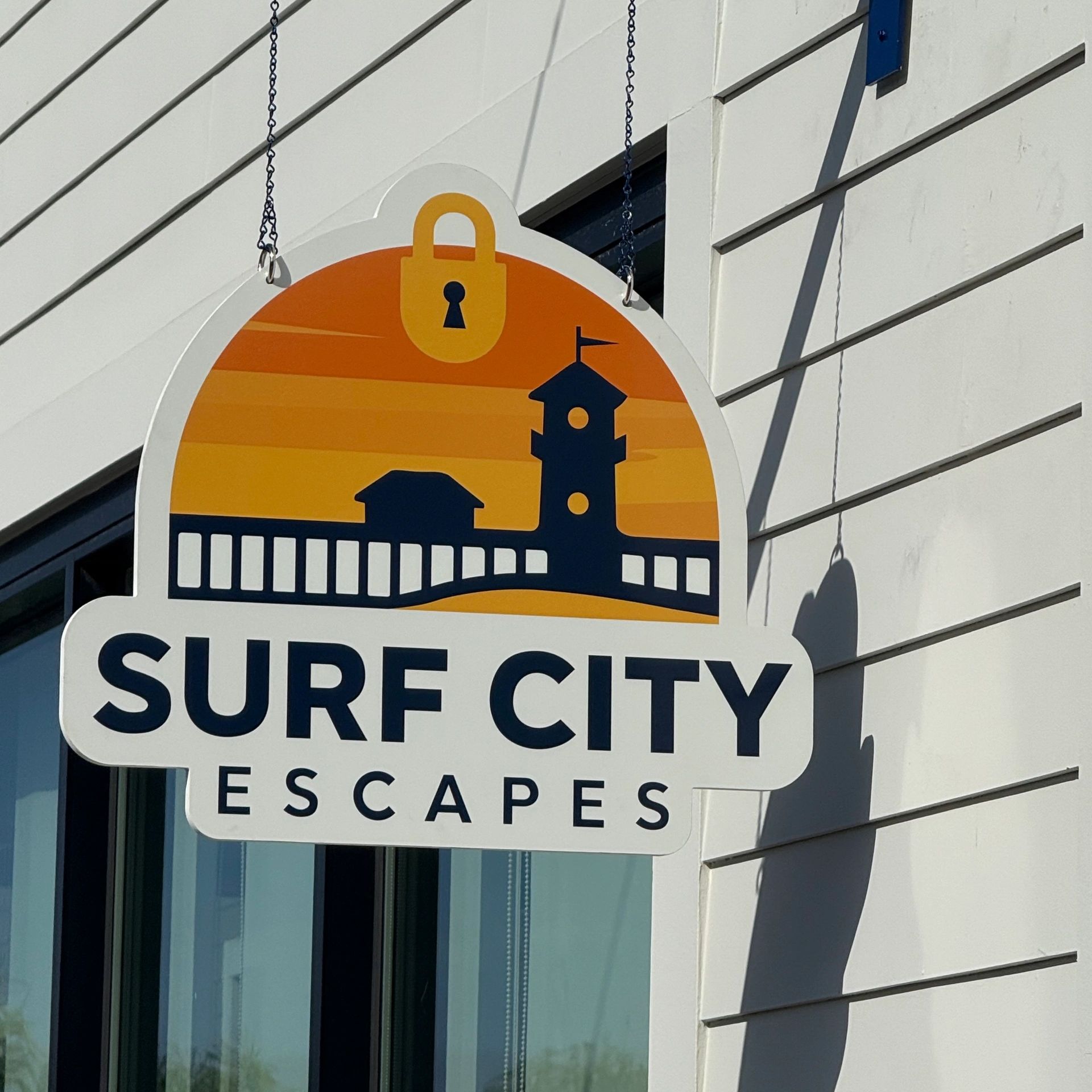 Sign for Surf City Escapes with a sunset and lock icon.