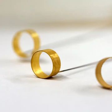 Golden rings casting long shadows on a white surface.