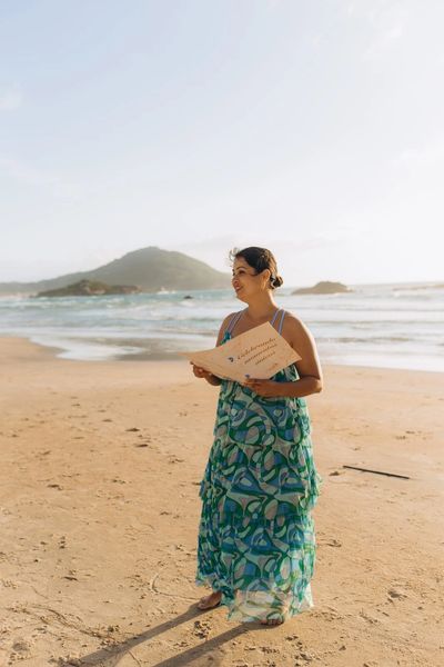 celebrante de casamento segurando sua pasta com textos e celebrando na areia da praia de Garopaba