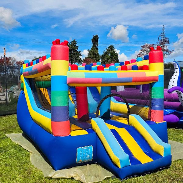 Colorful inflatable bounce house with slide outdoors on a sunny day.