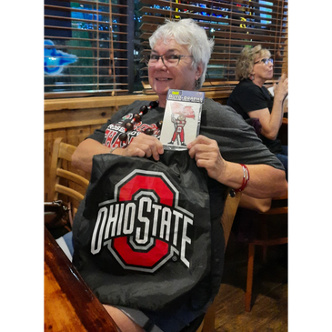 Smiling woman holding Ohio State memorabilia.