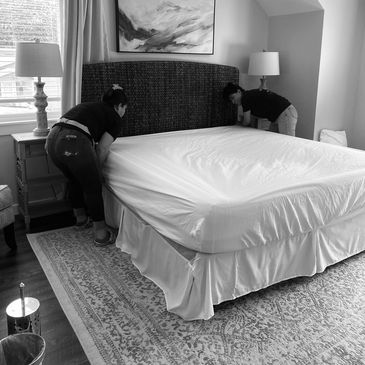 Two people making a bed in a bedroom with modern decor.