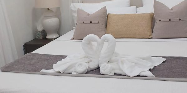 Two towel swans on a neatly made bed with decorative pillows.