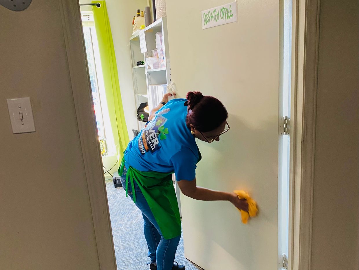 A woman cleaning a door labeled "Dispatch Office" with a yellow cloth.