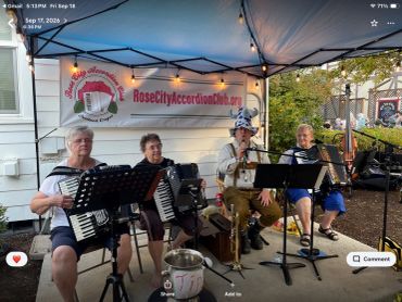 Four people playing accordions under a canopy.