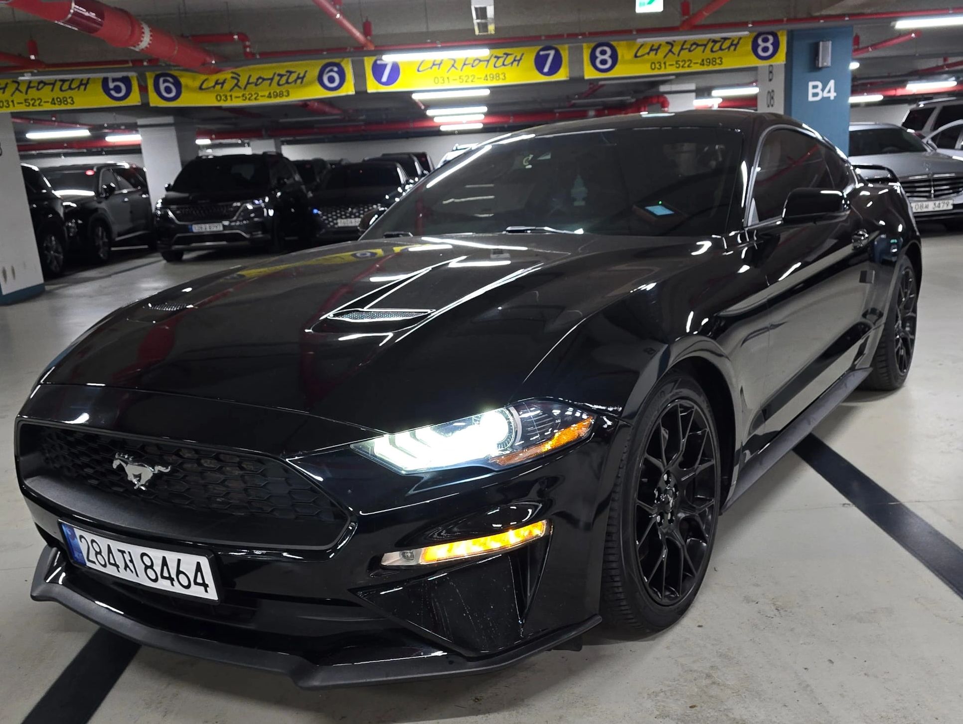 Mustang negro estacionado en un parqueadero subterráneo.