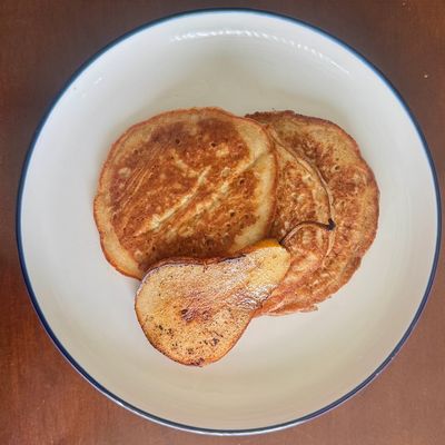 Pancakes with a roasted pear slice in a white bowl.