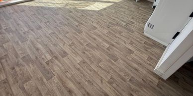 Wood-patterned vinyl flooring with a natural, warm tone.