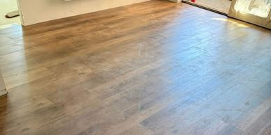 Empty room with newly installed wooden flooring and natural light.