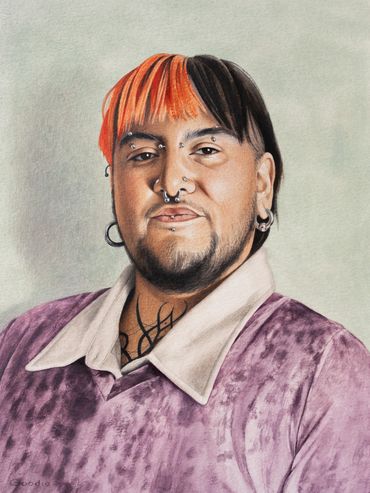Portrait of a person with half orange, half black hair and multiple piercings.