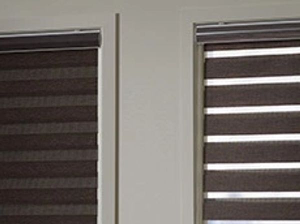 Modern living room with white furniture and brown striped blinds.