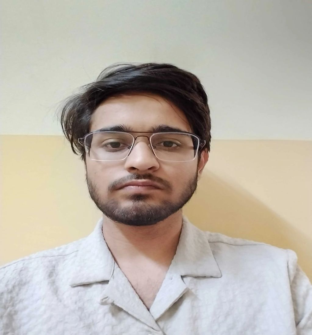 Young man with glasses and a beard wearing a light-colored shirt.